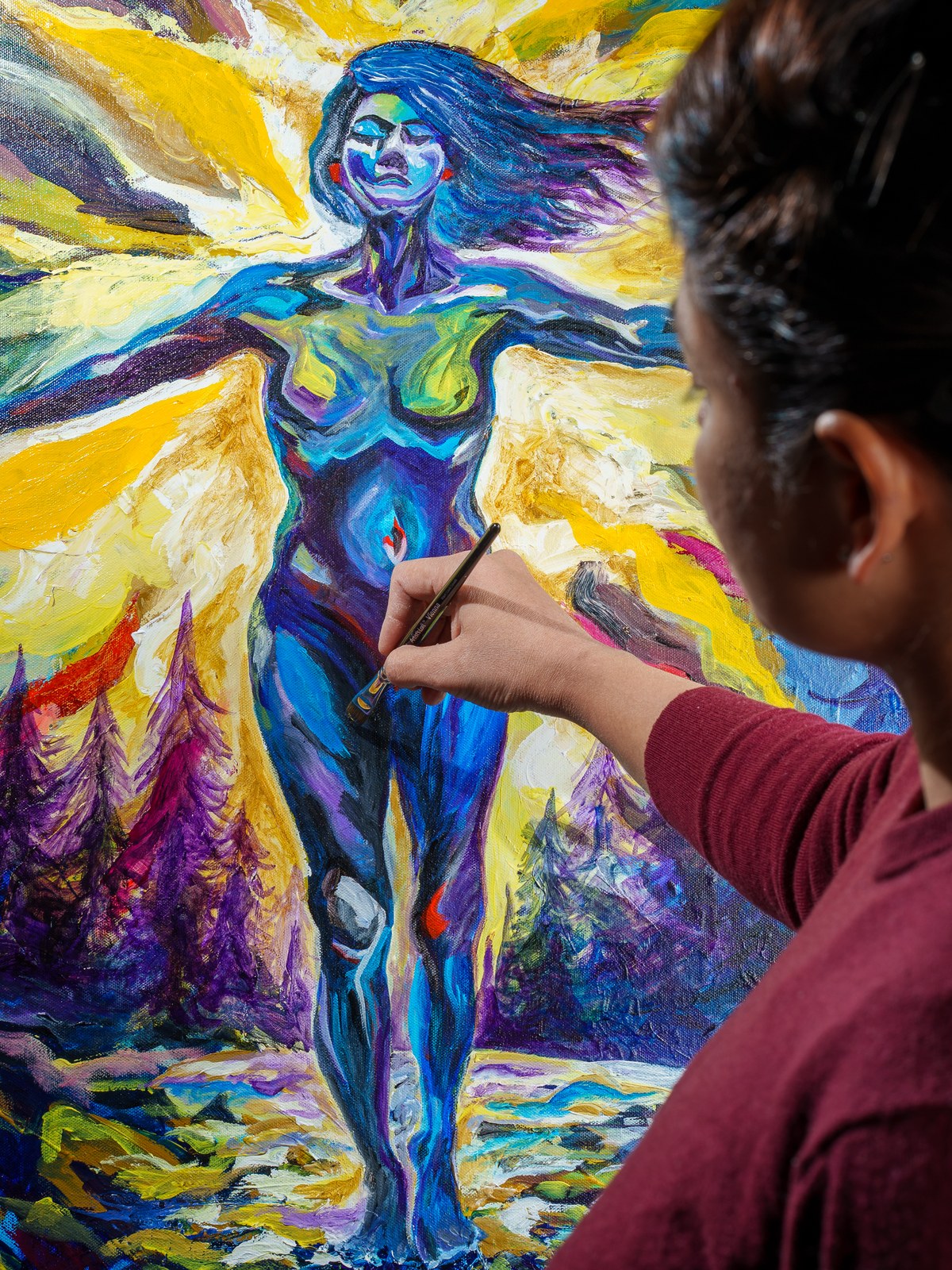 Artist's hand with brush hovers before the radiant blue figure mid-revision. Inverted Periscope, 2026, by Payal Agarwal.