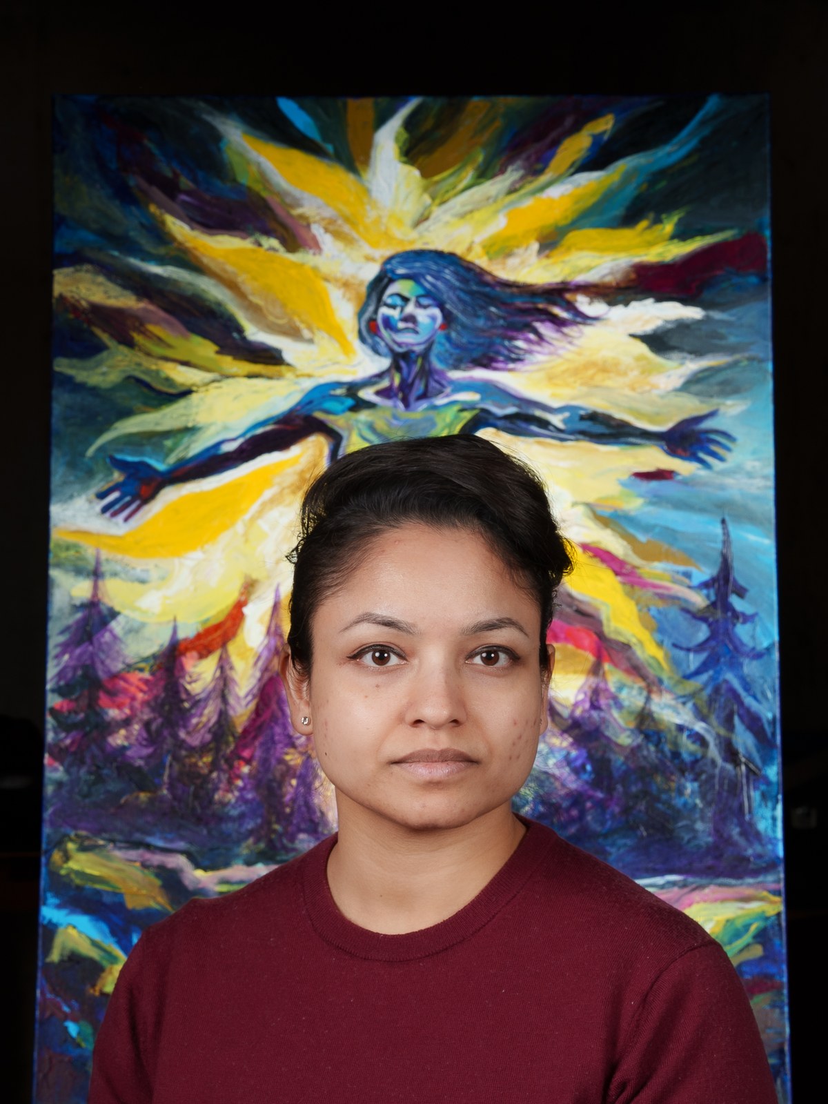 Payal Agarwal sits before her radiant blue figure, composed and direct. Inverted Periscope, 2026, by Payal Agarwal.