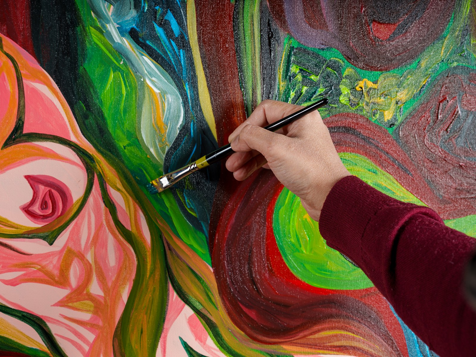 The artist's brush works wet acrylic into a seam of green and crimson, building the garden's consuming current. The Garden Consumes, 2026, by Payal Agarwal.