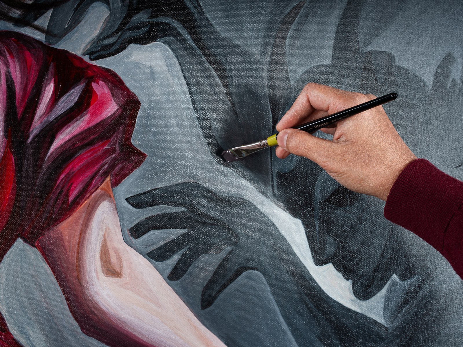 Payal's hand glides a palette knife across the grey shadow field surrounding the figure's arm. The Gravity of Touch, 2026, by Payal Agarwal.