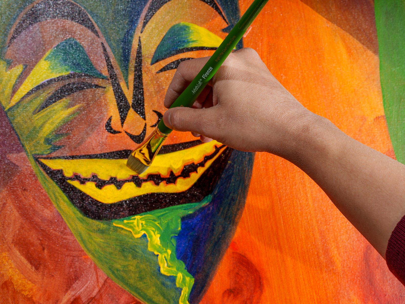 The artist's hand refining the grinning mask's jagged smile mid-brushstroke. The Repertoire, 2026, by Payal Agarwal.