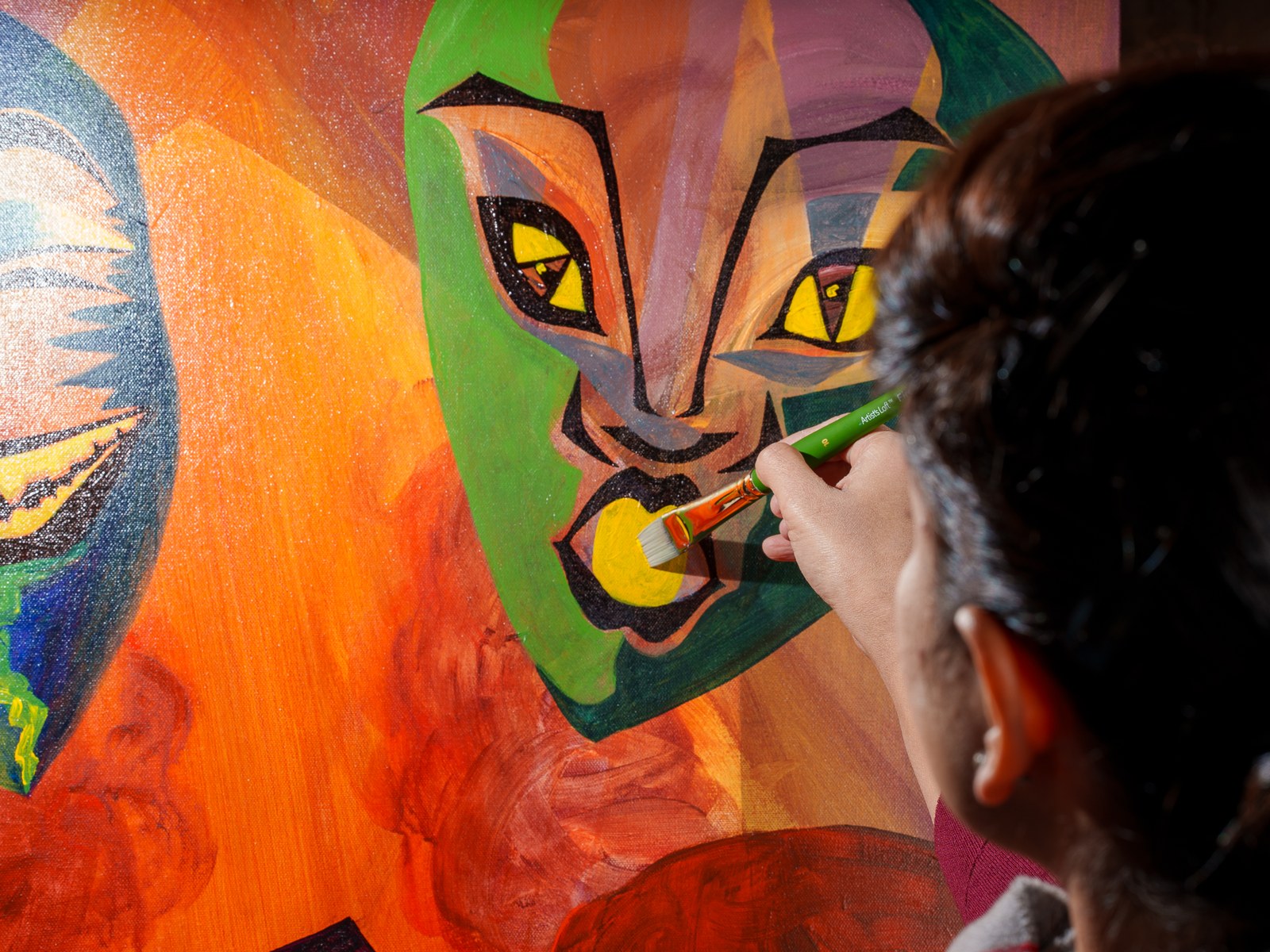 Payal at work on the cold feline mask, brush loaded with cadmium yellow. The Repertoire, 2026, by Payal Agarwal.